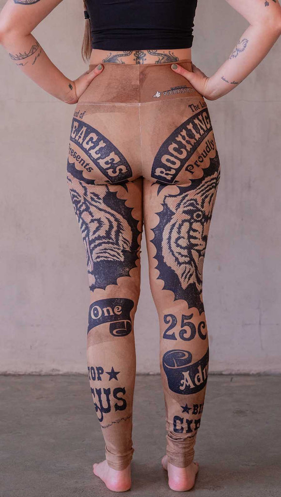 Model wearing WERKSHOP Tiger Ticket leggings featuring original and exclusive artwork depicting a vintage ticket to the circus! With a black sketch of a tiger over a distressed burnt orange background. 
