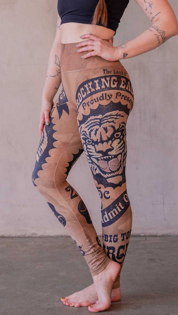Model wearing WERKSHOP Tiger Ticket leggings featuring original and exclusive artwork depicting a vintage ticket to the circus! With a black sketch of a tiger over a distressed burnt orange background. 