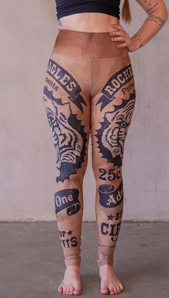 Model wearing WERKSHOP Tiger Ticket leggings featuring original and exclusive artwork depicting a vintage ticket to the circus! With a black sketch of a tiger over a distressed burnt orange background. 