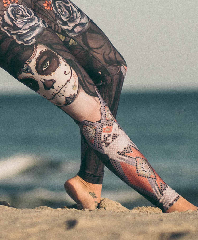 Yogi doing "wildthing" pose at the beach while wearing WERKSHOP Dark Sugar Full Length Triathlon Leggings