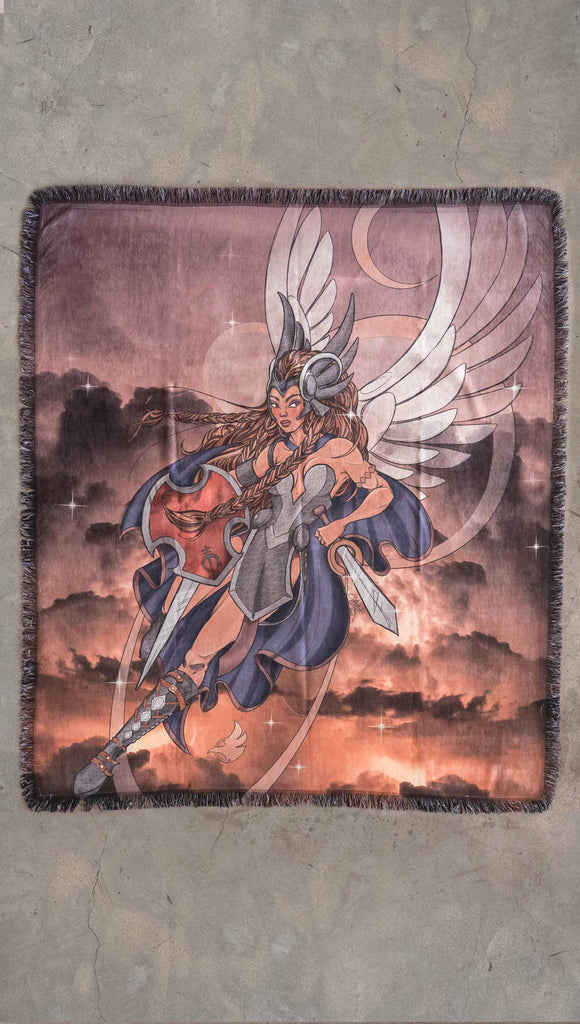 Decorative Chenille Tapestry printed with limited edition artwork by our Female Founder, Chriztina Marie. The artwork features a valyrkie warrior flying through a stormy sky holding a sword and shield. The colours are rich and warm with peach/orange tones and some pops of blue. This image shows the tapestry laid flat on the floor.