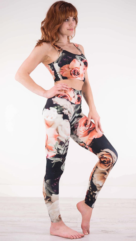 Right view of model wearing black athleisure leggings with pink and white roses and leafy greens throughout