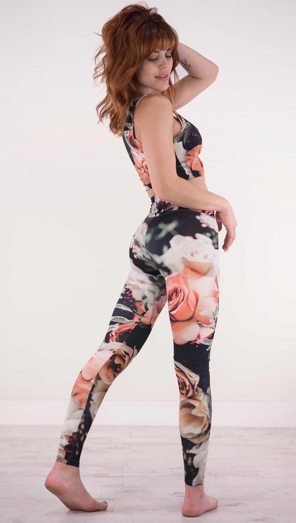 Back view of model wearing black athleisure leggings with pink and white roses and leafy greens throughout
