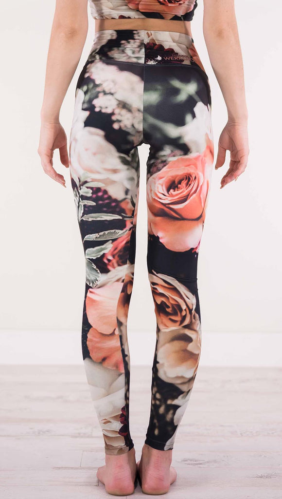 Back view of model wearing black athleisure leggings with pink and white roses and leafy greens throughout