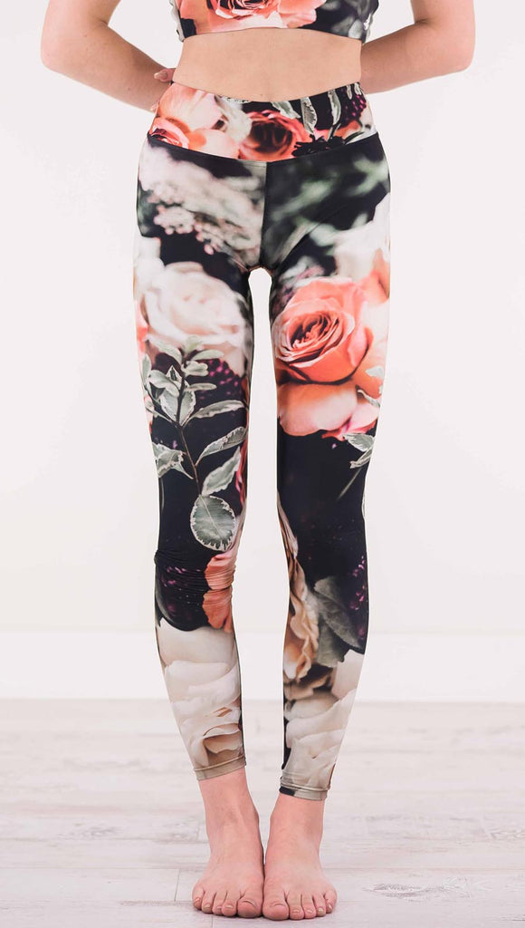 Front view of model wearing triathlon black leggings with pink and white roses and leafy greens throughout