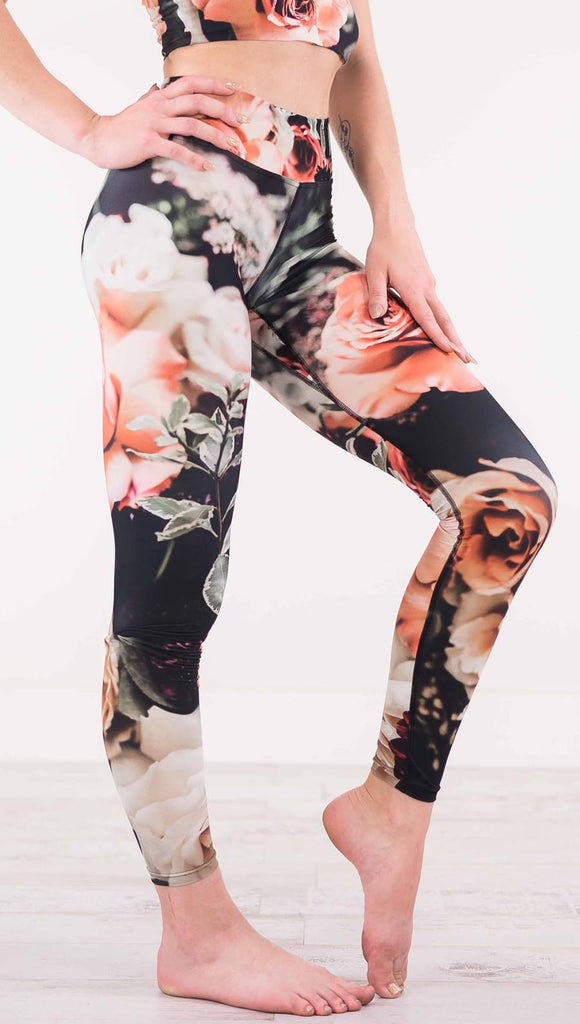 Right view of model wearing black triathlon leggings with pink and white roses and leafy greens throughout