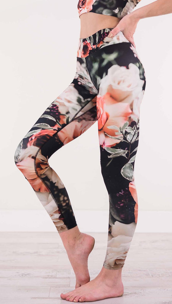 Enhanced left view of model wearing black triathlon leggings with pink and white roses and leafy greens throughout