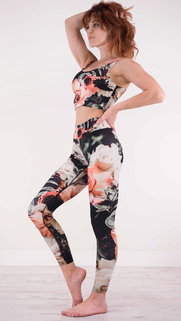 Left view of model wearing black traithlon legging with pink and white roses and leafy greens throughout