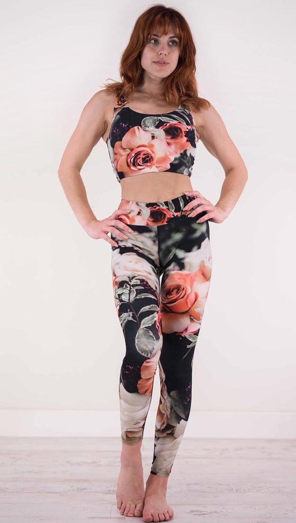 Front view of model wearing black triathlon leggings with pink and white roses and leafy greens throughout
