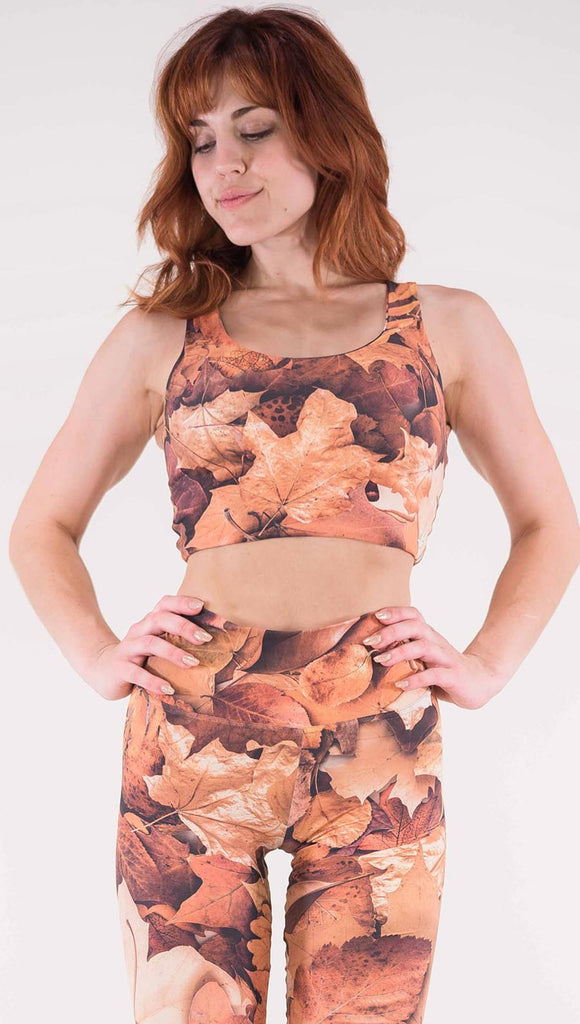 Front view of model wearing the Bodacious Bouquet reversible crop top in the Autumn Leaves side. It has different shades of orange in autumn leaves throughout the top