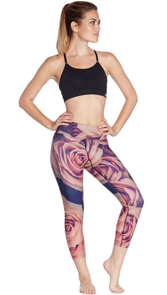 front view of model wearing printed capri leggings with all-over rose design motif and sports top
