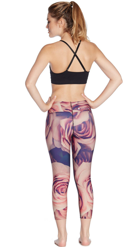 back view of model wearing printed capri leggings with all-over rose design motif and sports top