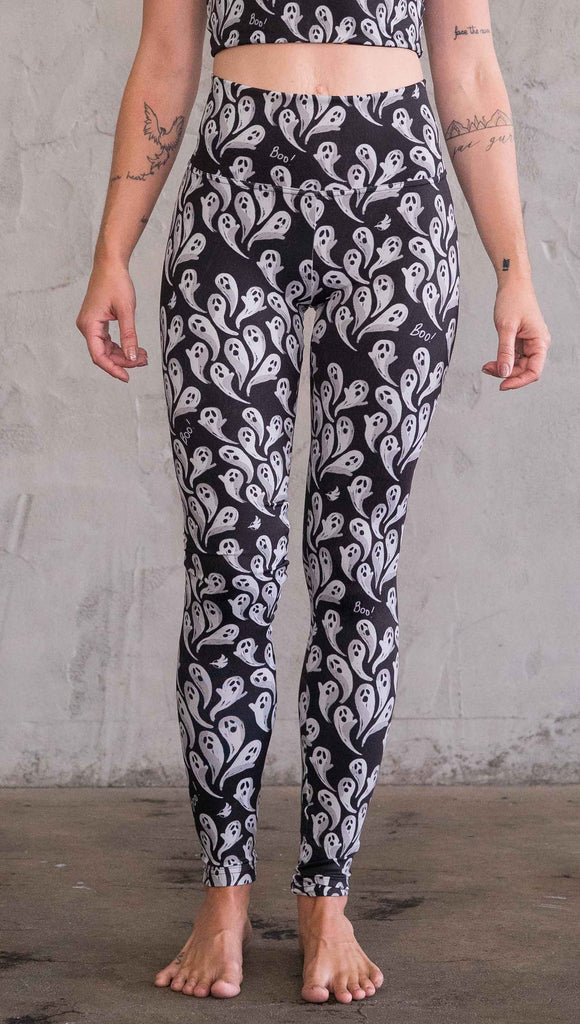 Front view of model wearing black athleisure leggings with little white ghosts and the word, "Boo!" in a repeat pattern