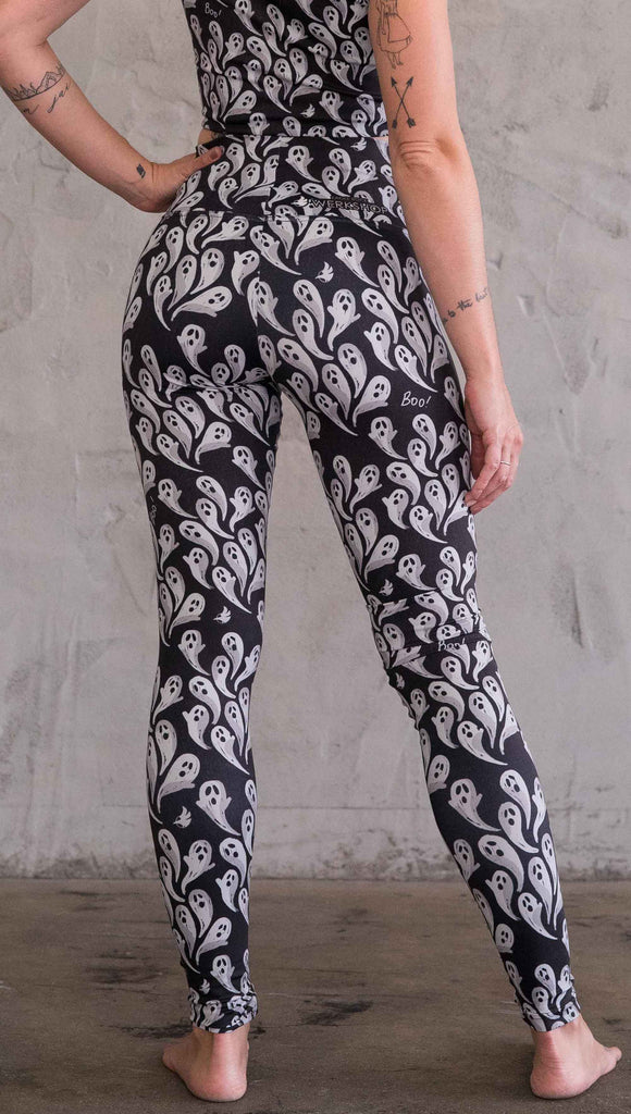Back view of model wearing black athleisure leggings with little white ghosts and the word, "Boo!" in a repeat pattern