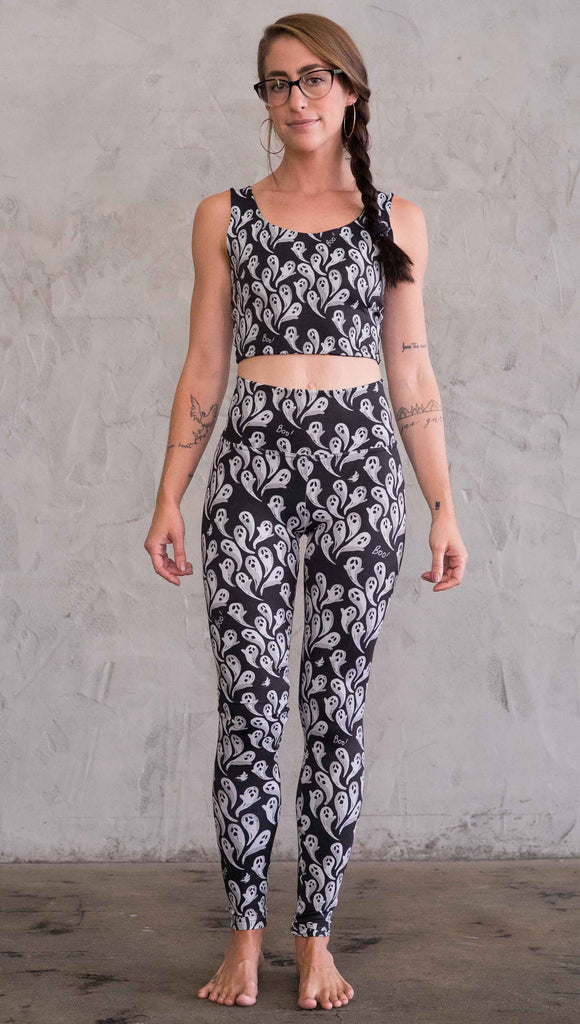 Front view of model wearing black athleisure leggings with little white ghosts and the word, "Boo!" in a repeat pattern