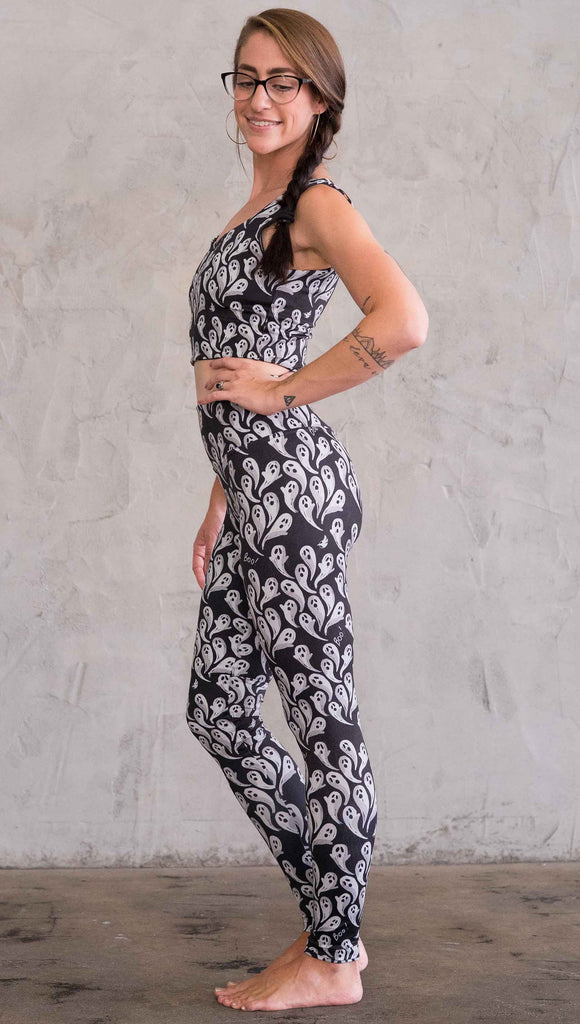 Left view of model wearing black athleisure leggings with little white ghosts and the word "Boo!" in a repeat pattern