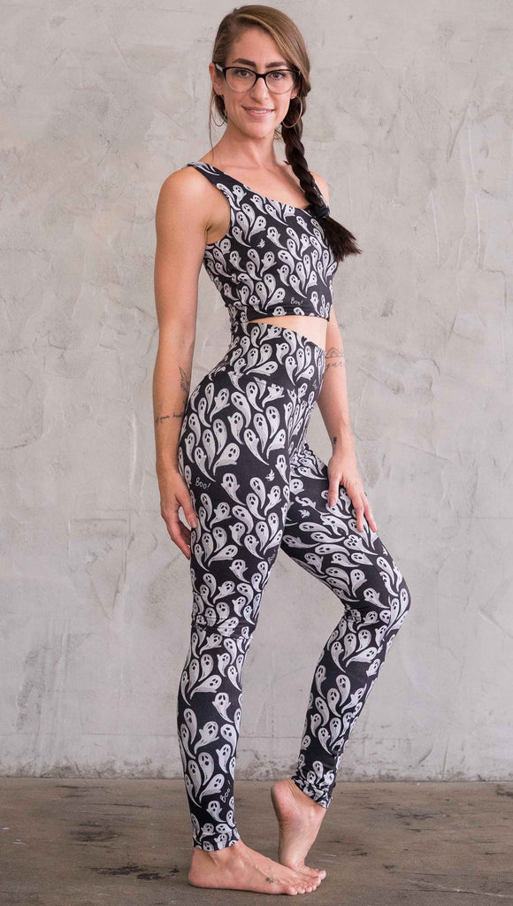 Right view of model wearing the black athleisure leggings with little white ghosts and the word, "Boo!" in a repeat pattern