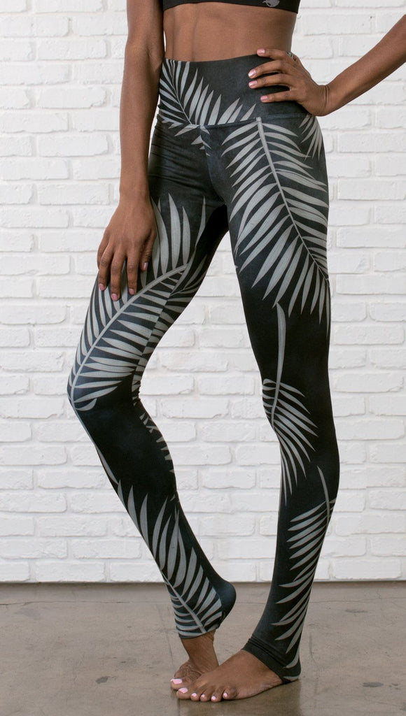 close up slightly turned front view of model wearing full length black leggings with white palm design