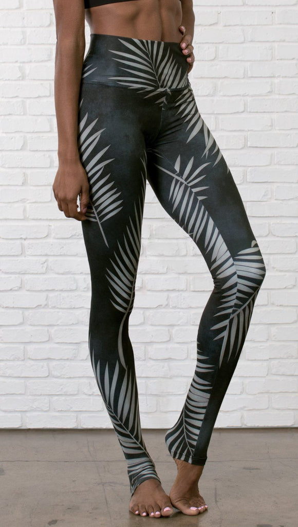 closeup slightly turned front view of model wearing full length black leggings with white palm design