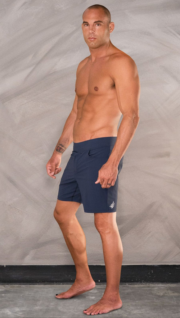 Left side view of model wearing men's blue performance shorts with slim fit.