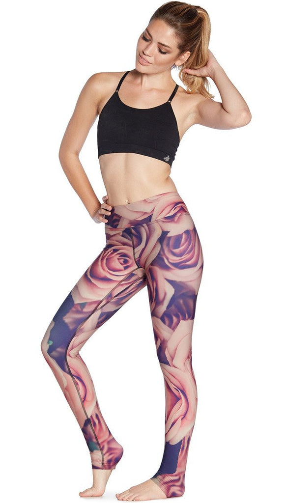 front view of model wearing printed full length leggings with all-over rose design motif and sports top