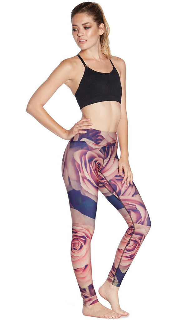 slightly turned front view of model wearing printed full length leggings with all-over rose design motif and sports top