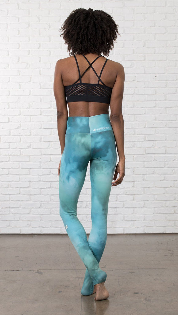 back view of model wearing water / ocean themed printed full length leggings with black sports top