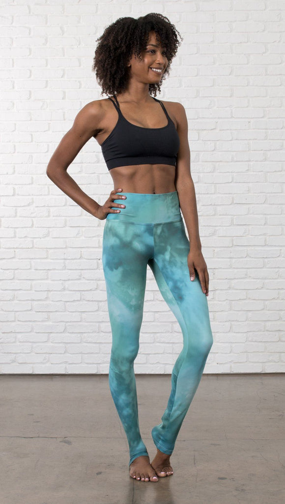 front view of model wearing water / ocean themed printed full length leggings with black sports top