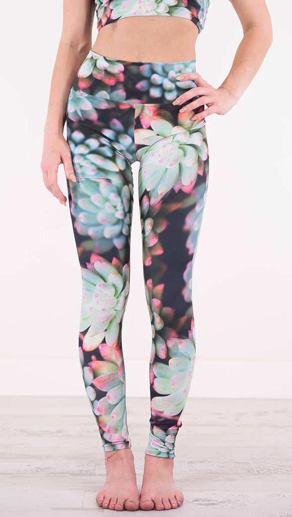 Front view of model wearing black athleisure leggings with green succulent plants with pink tips throughout