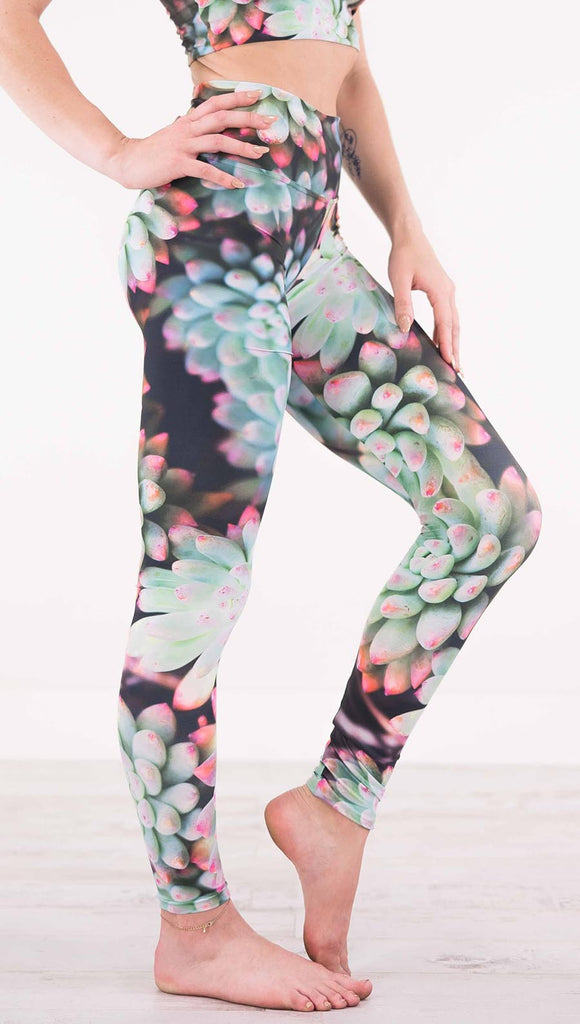 Right view of model wearing black athleisure leggings with green succulent plants with pink tips throughout