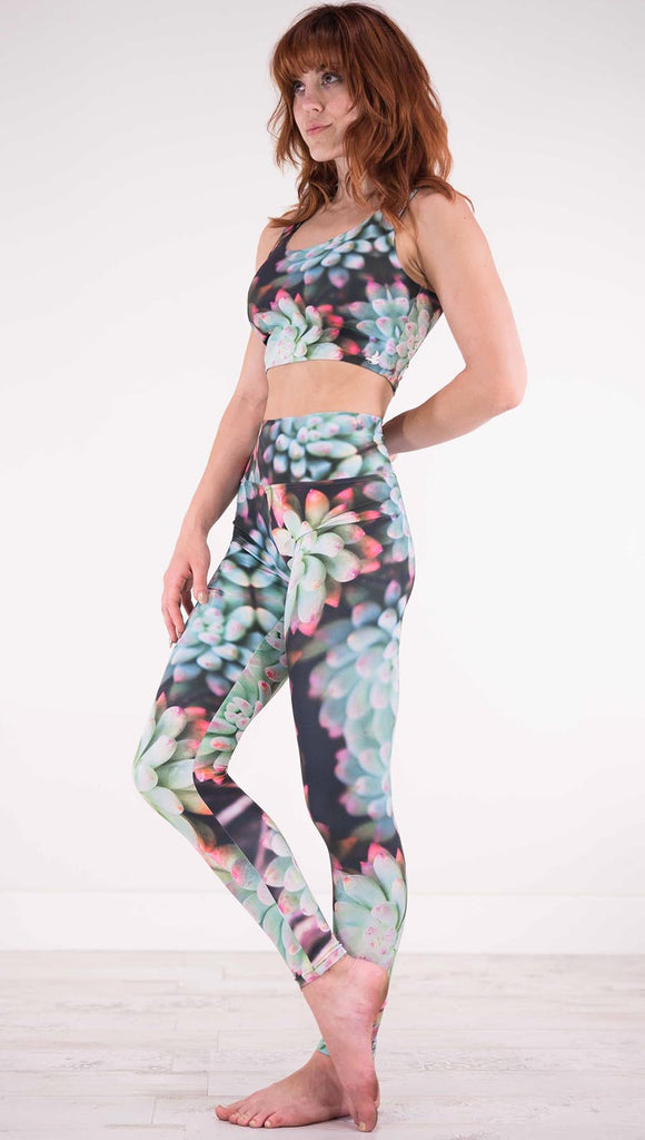 Left view of model wearing black athleisure leggings with green succulent plants with pink tips throughout