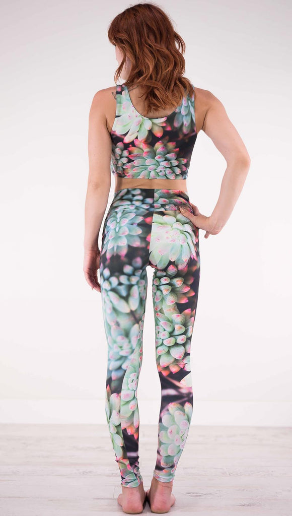 Back view of model wearing black athleisure leggings with green succulent plants with pink tips throughout and the matching top