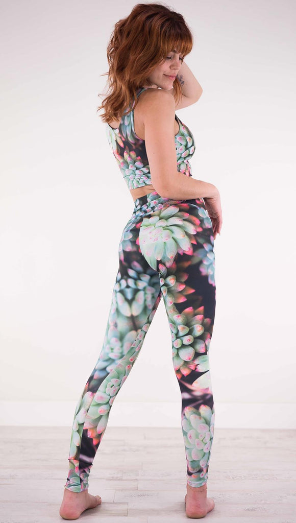 Back view of model wearing black athleisure leggings with green succulent plants with pink tips throughout