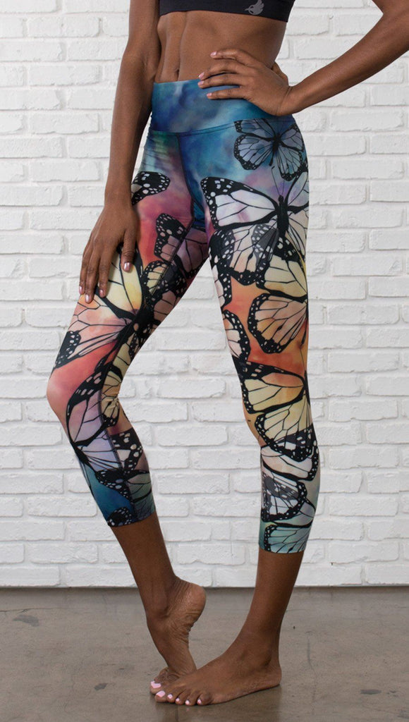 closeup left side view of model wearing colorful butterfly themed printed capri triathlon leggings