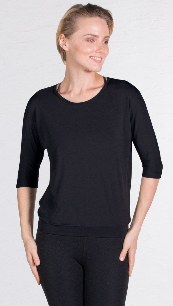 closeup front view of model wearing 3/4 Sleeve black Performance Top with Open Back and Loose / Athleisure Fit