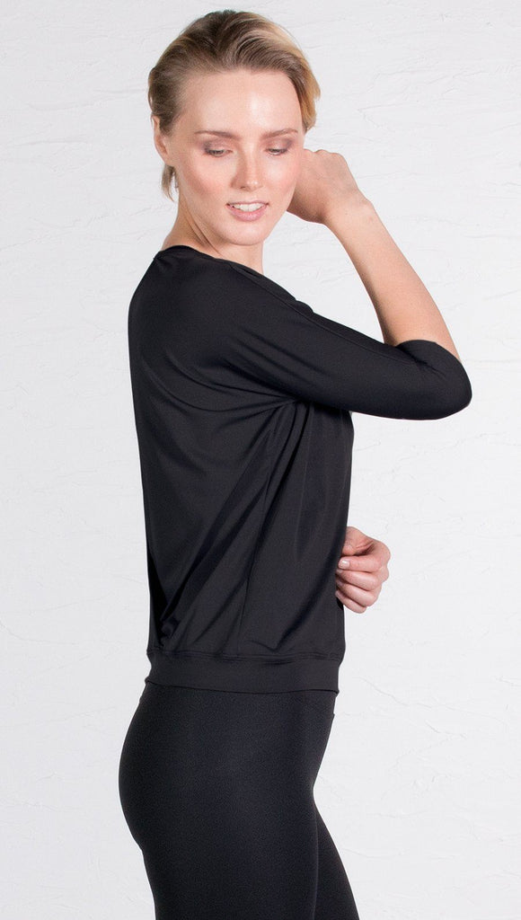 closeup right side view of model wearing 3/4 black Sleeve Performance Top with Open Back and Loose / Athleisure Fit