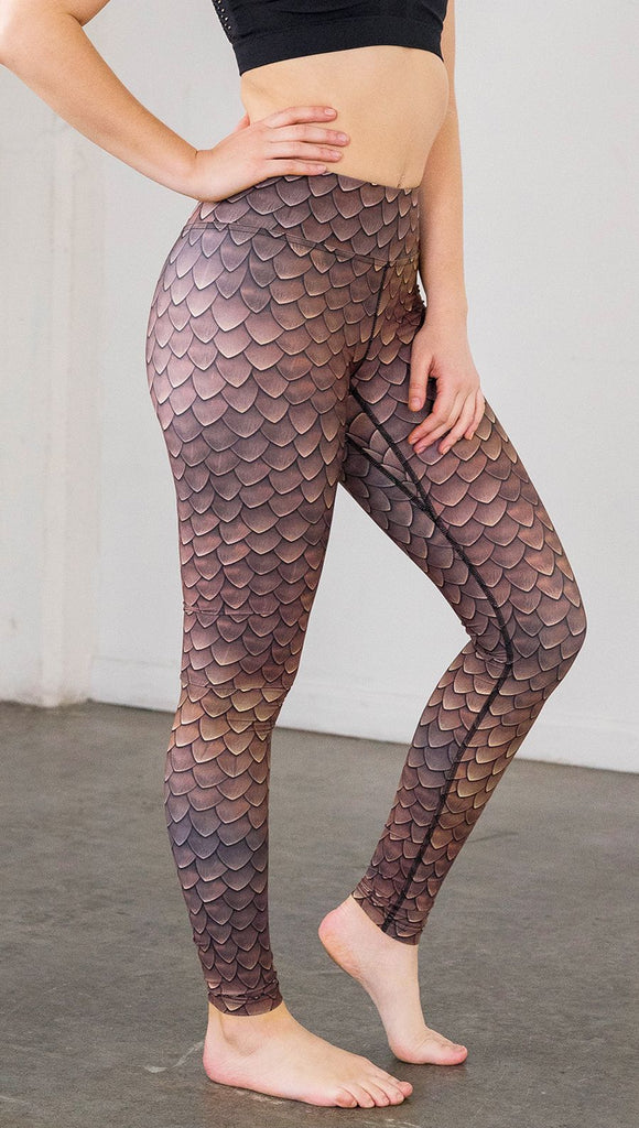 Right side view of model wearing brown dragon scale printed full length leggings