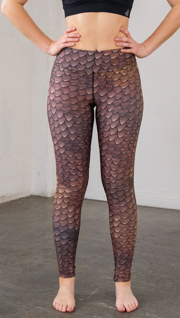 Front view of model wearing brown dragon scale printed full length leggings