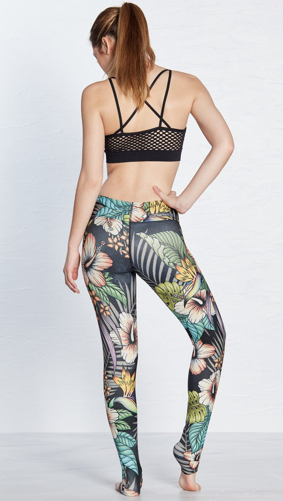 close up left side view of model wearing printed full length leggings with tropical floral design and black background