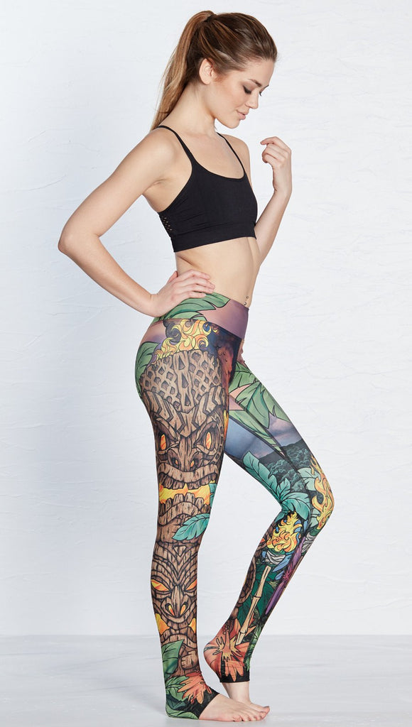 right side view of model wearing island tiki themed printed full length leggings