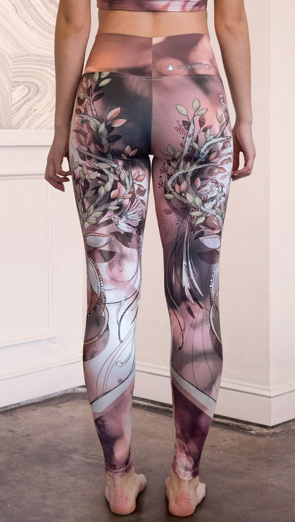 Back view of model wearing full length athleisure leggings with a deer on it. They are a purple and orange color with tree branches as the antlers and birds on the antlers