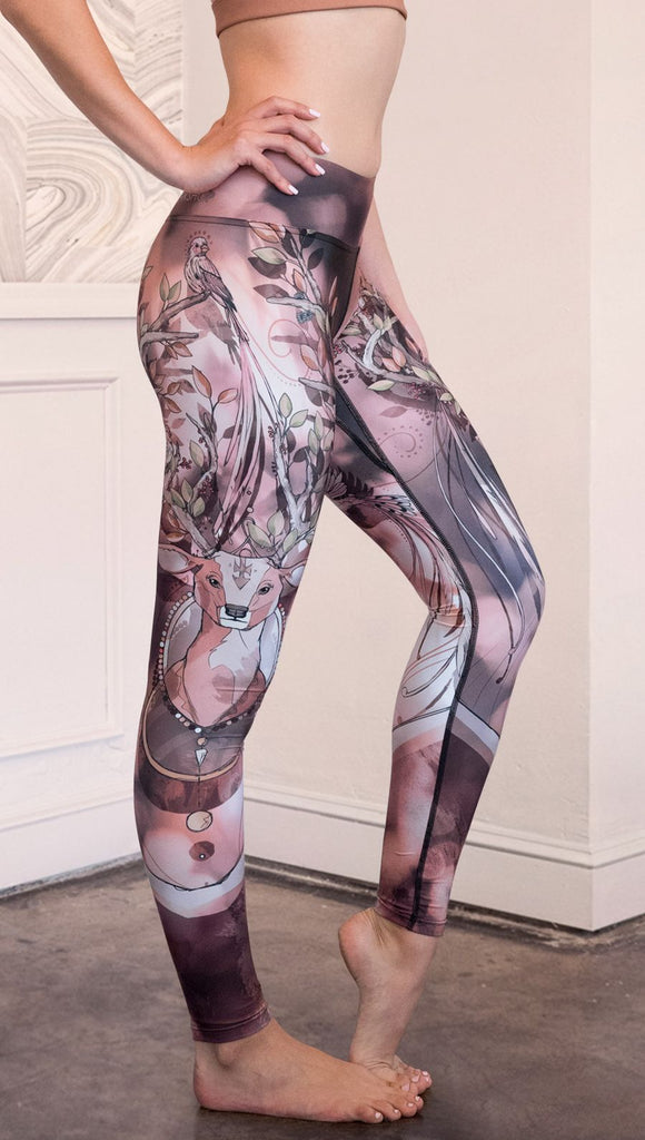 Right side view of model wearing full length triathlon leggings with a deer on it. They are a purple and orange color with tree branches as the antlers and birds on the antlers