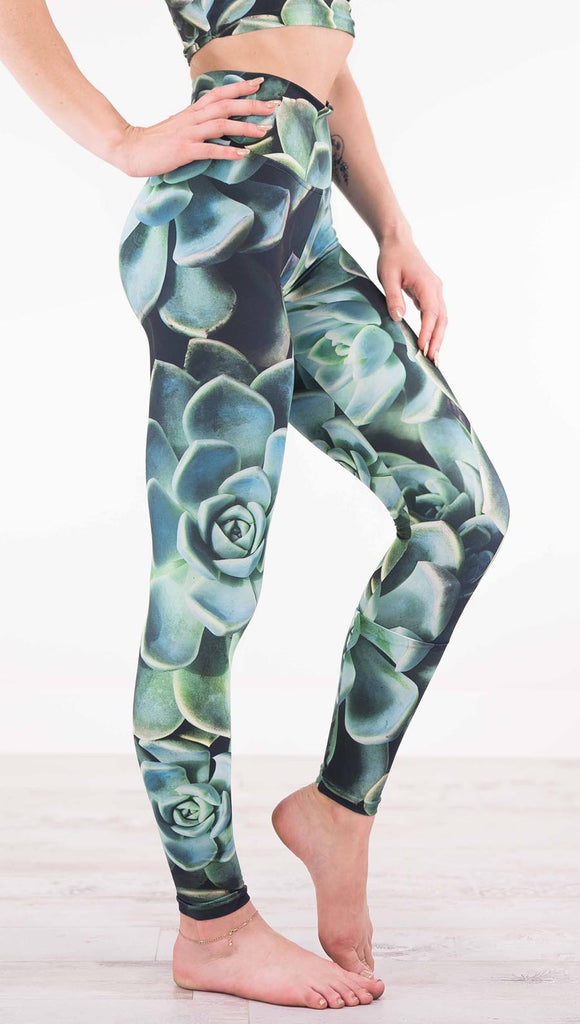 Right view of model wearing black athleisure leggings with green succulent plants throughout