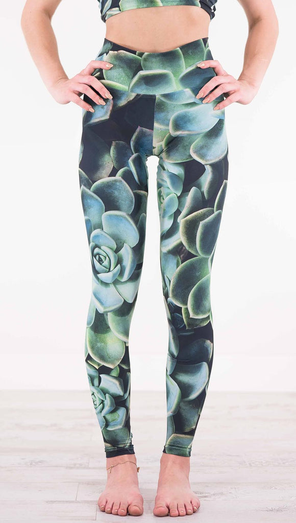 Front view of model wearing black athleisure leggings with green succulent flowers throughout