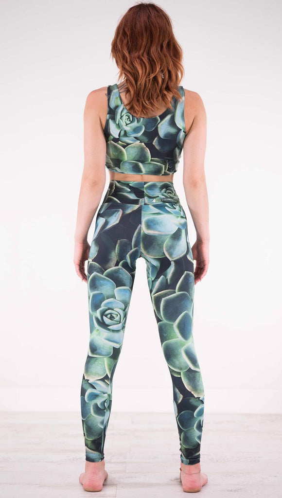 Back view of model wearing black athleisure leggings with green succulent plants throughout