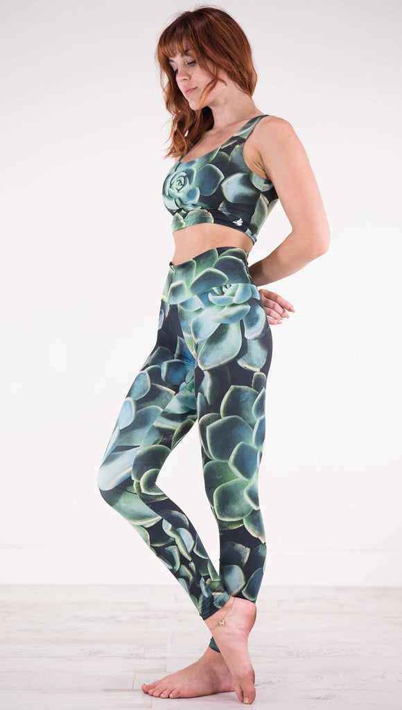 Left view of model wearing black athleisure leggings with green succulent plants throughout