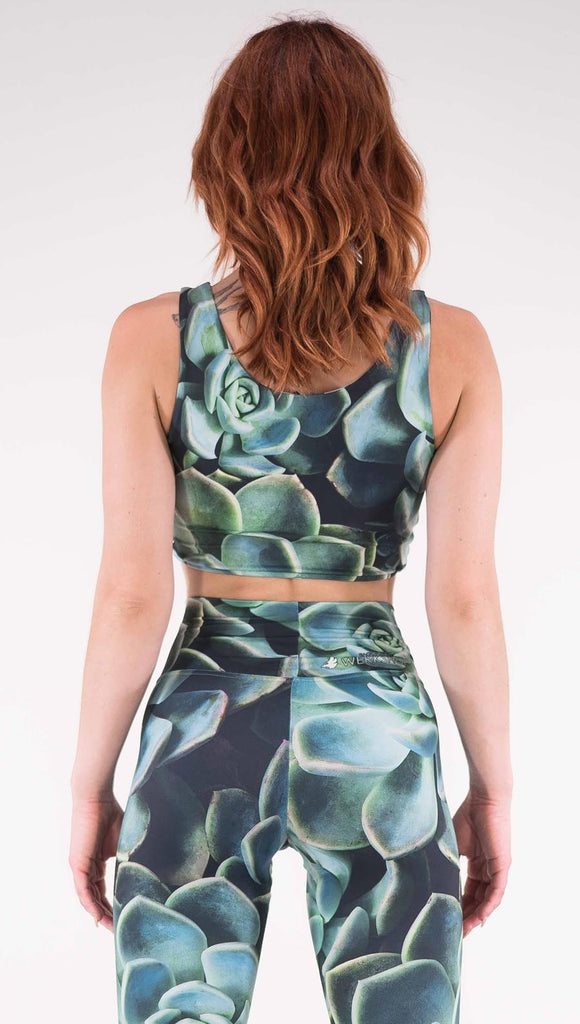 Back view of model wearing the reversible Coachella Sunset Top. This is the Green Envy side, it is a black crop top with green succulent plants throughout