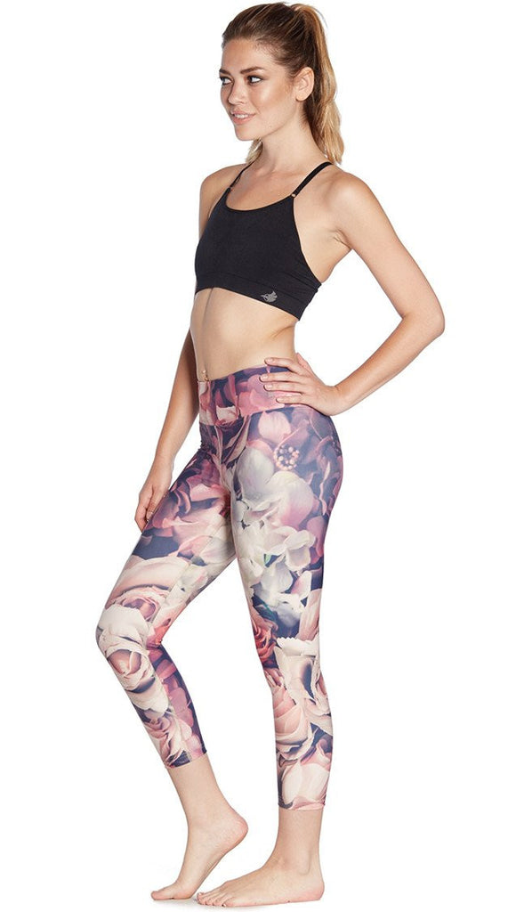 left side view of model wearing pink floral printed capri leggings