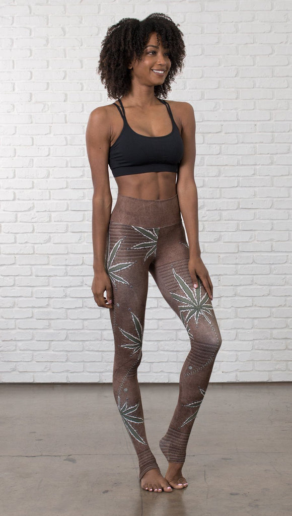 close up slightly turned front view of model wearing cannabis leaf printed full length leggings