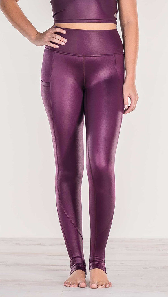 Close up front view of model wearing shiny eggplant purple colored full length leggings with right side pocket